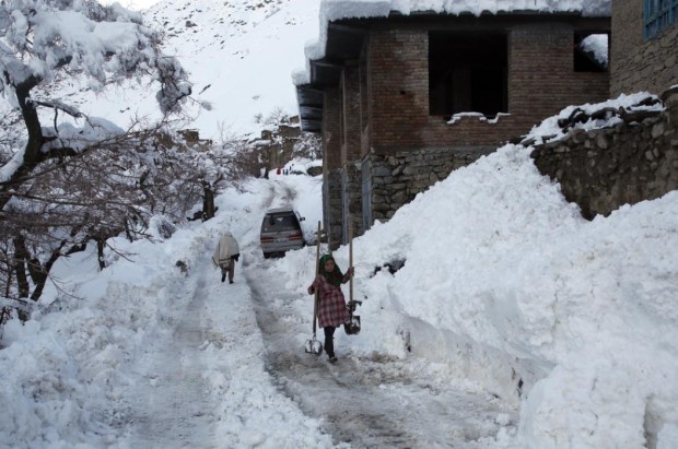 An Afghan girl carries shovels in a village close to an avalanche site in Panjshir province north of Kabul, Afghanistan, Wednesday, Feb. 25, 2015. Avalanches caused by a heavy winter snow killed at least 124 people in northeastern Afghanistan, an emergency official said Wednesday, as rescuers clawed through debris with their hands to save those buried beneath. (AP Photo/Massoud Hossaini)