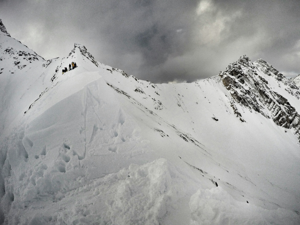 Skiers and boarders atop Bruins Ridge in Glacier National Park following an avalanche on Sunday that slid down the slope on the right. Photo: colebullock7 via Avalanche Canada Mountain Information Network