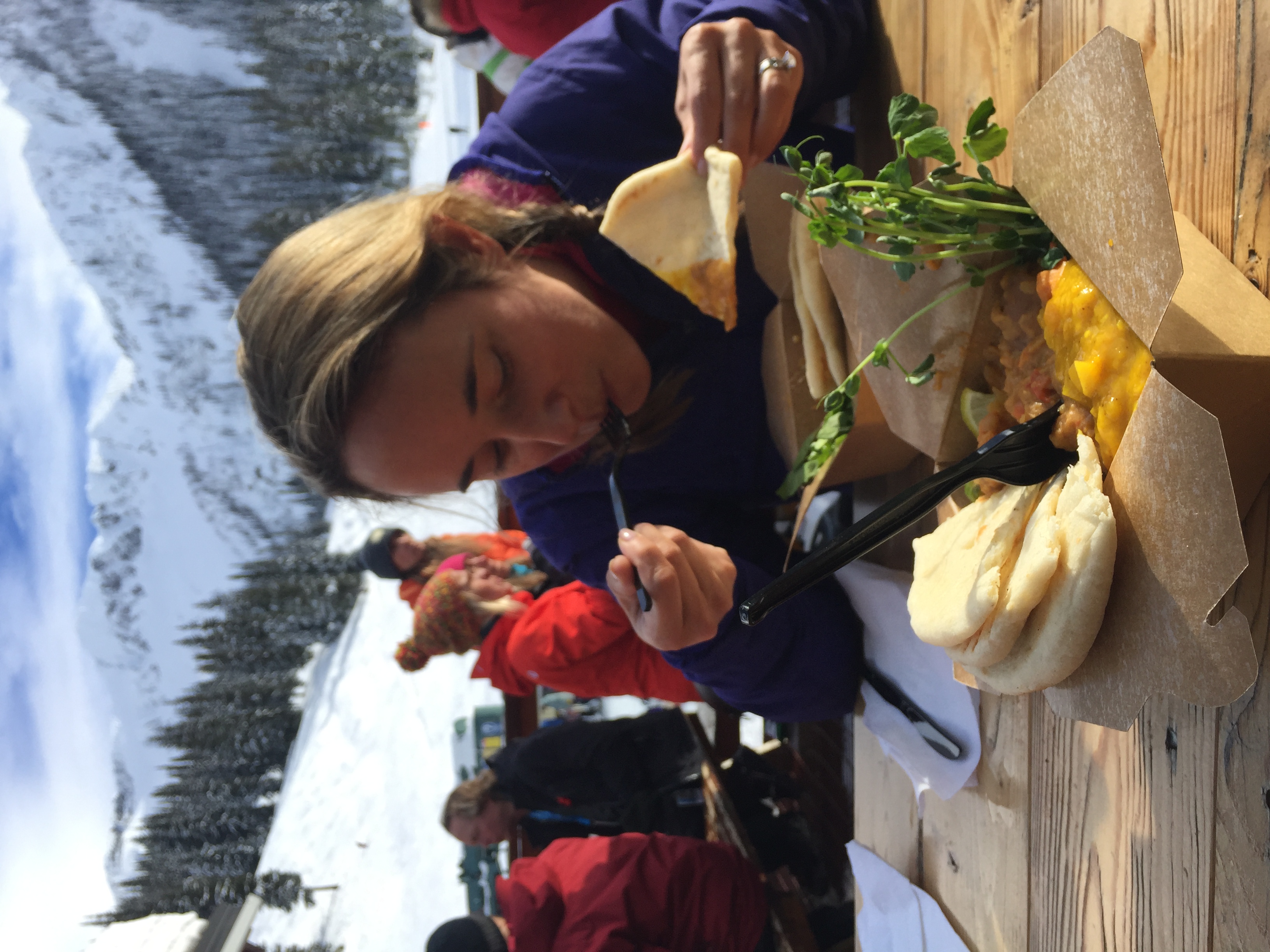 Jenny enjoying her Backside Bowl Curry. Ymir Peak in the background.