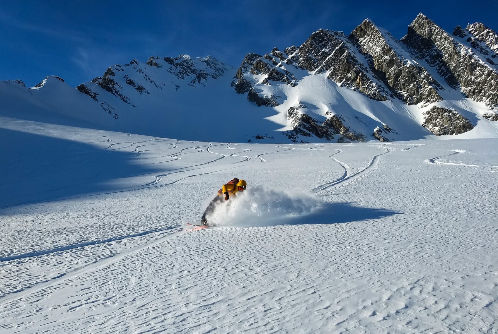 snowboarder carving through snow on swiss glacier