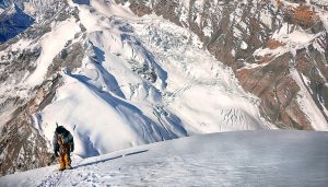 Mountain climber is shown on an exposed slope, high above a glacier. 