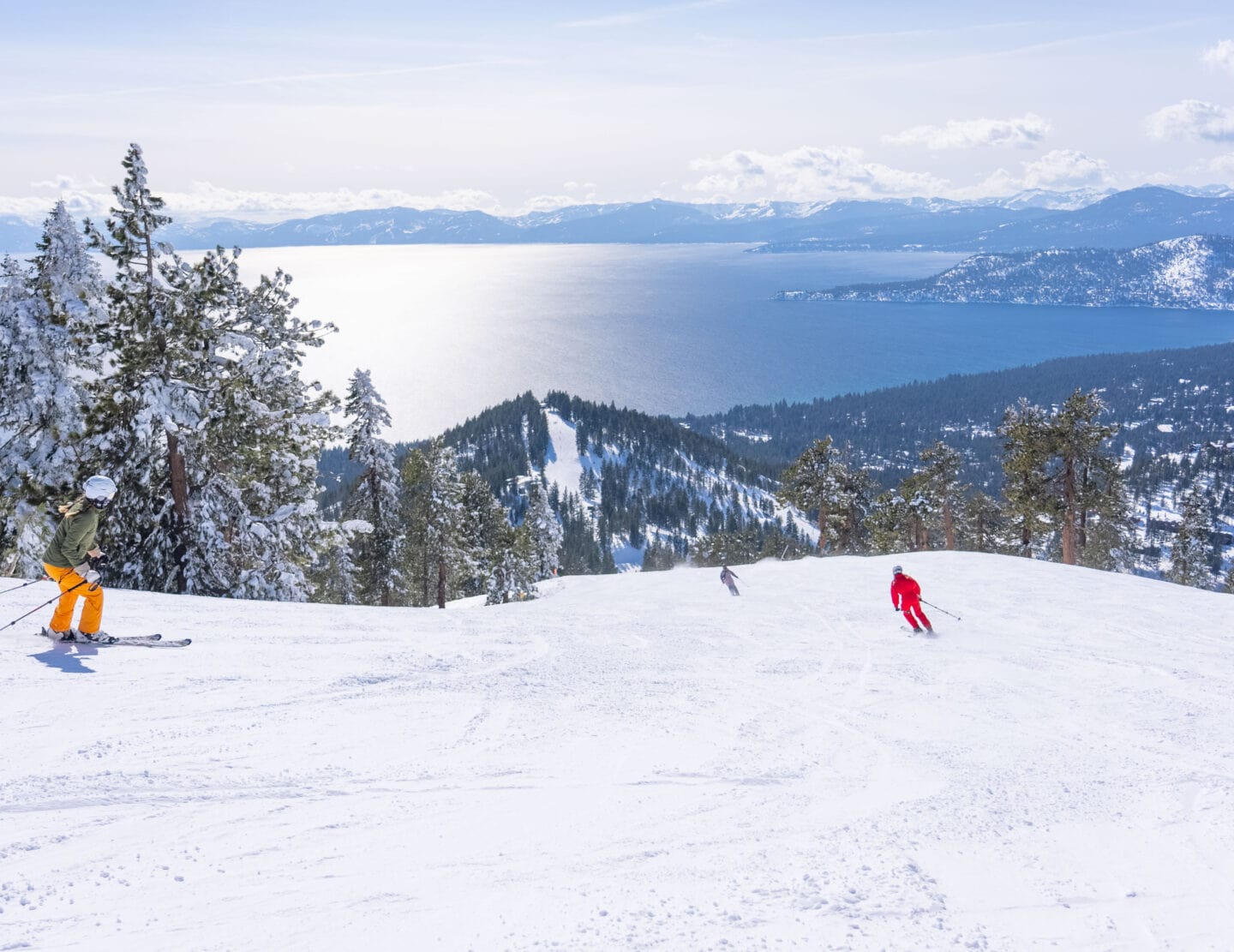 Skiers at Diamond Peak making turns with the lake in the background.