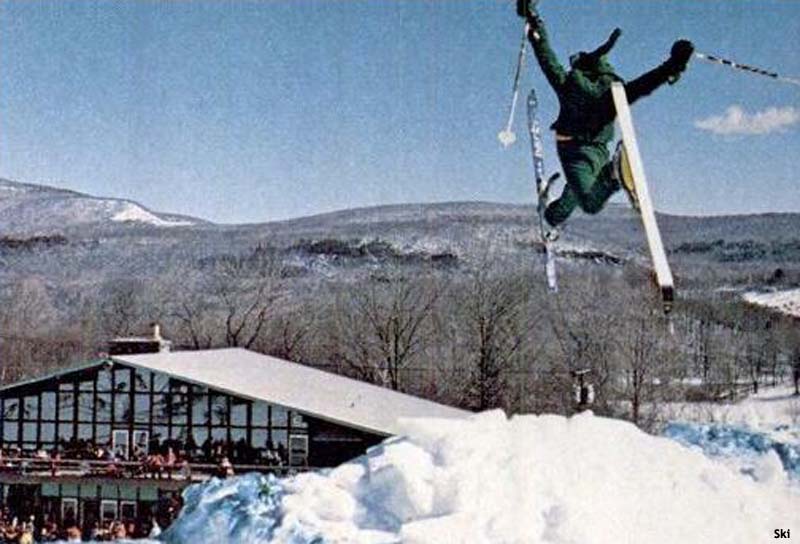 skier in the air with Brodie Mountain base area in background