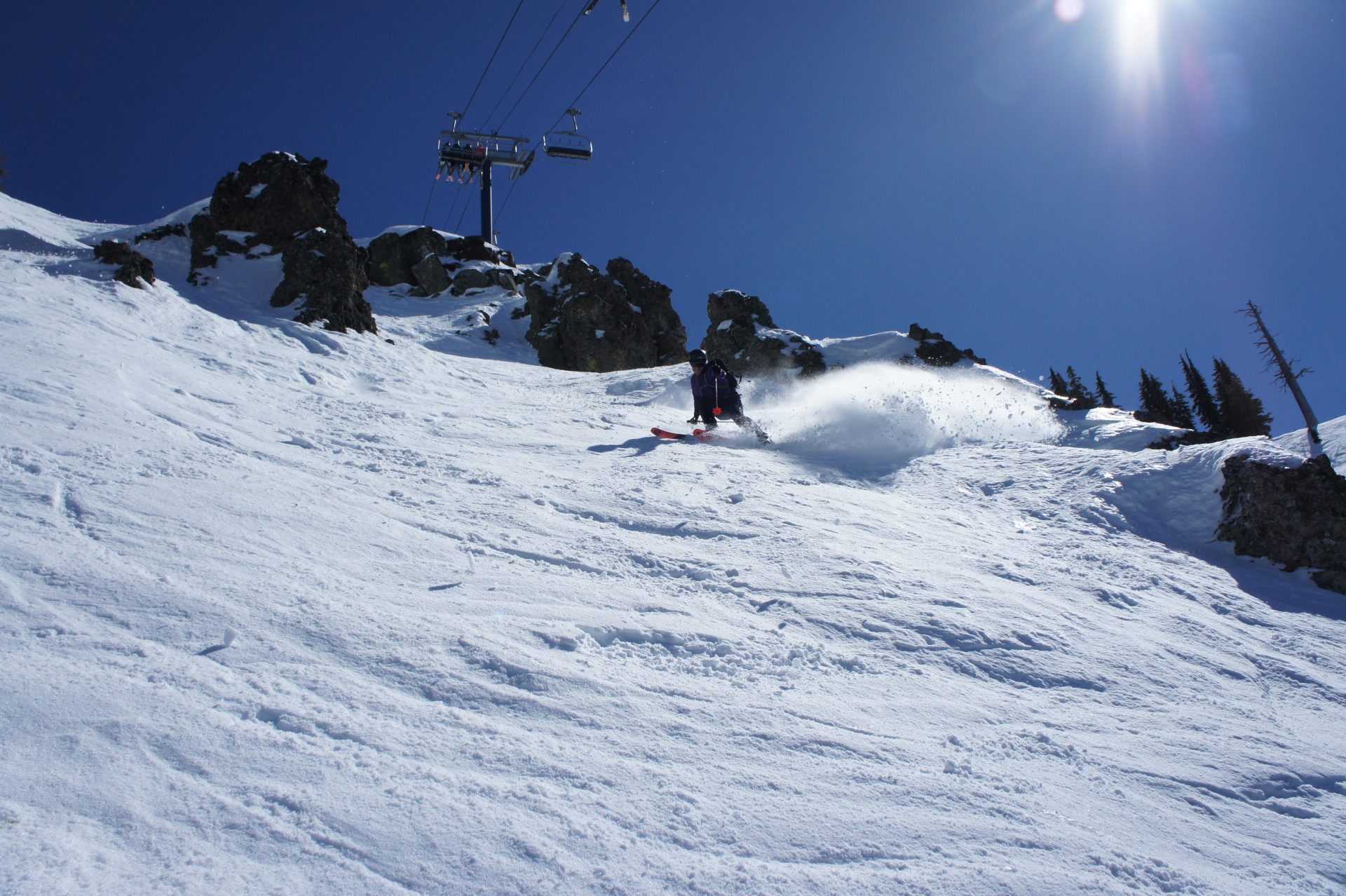 skier exiting rock chute underneath chairlift