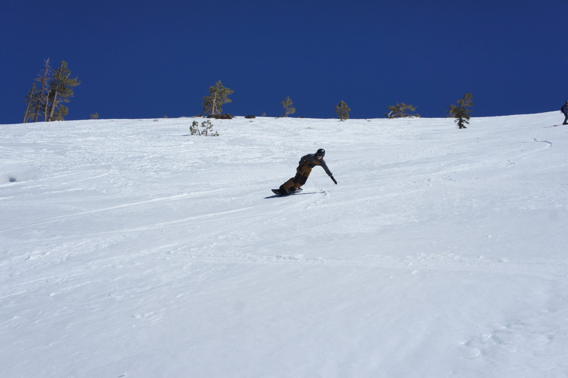 snowboarder laying out in a turn on a bluebird spring day
