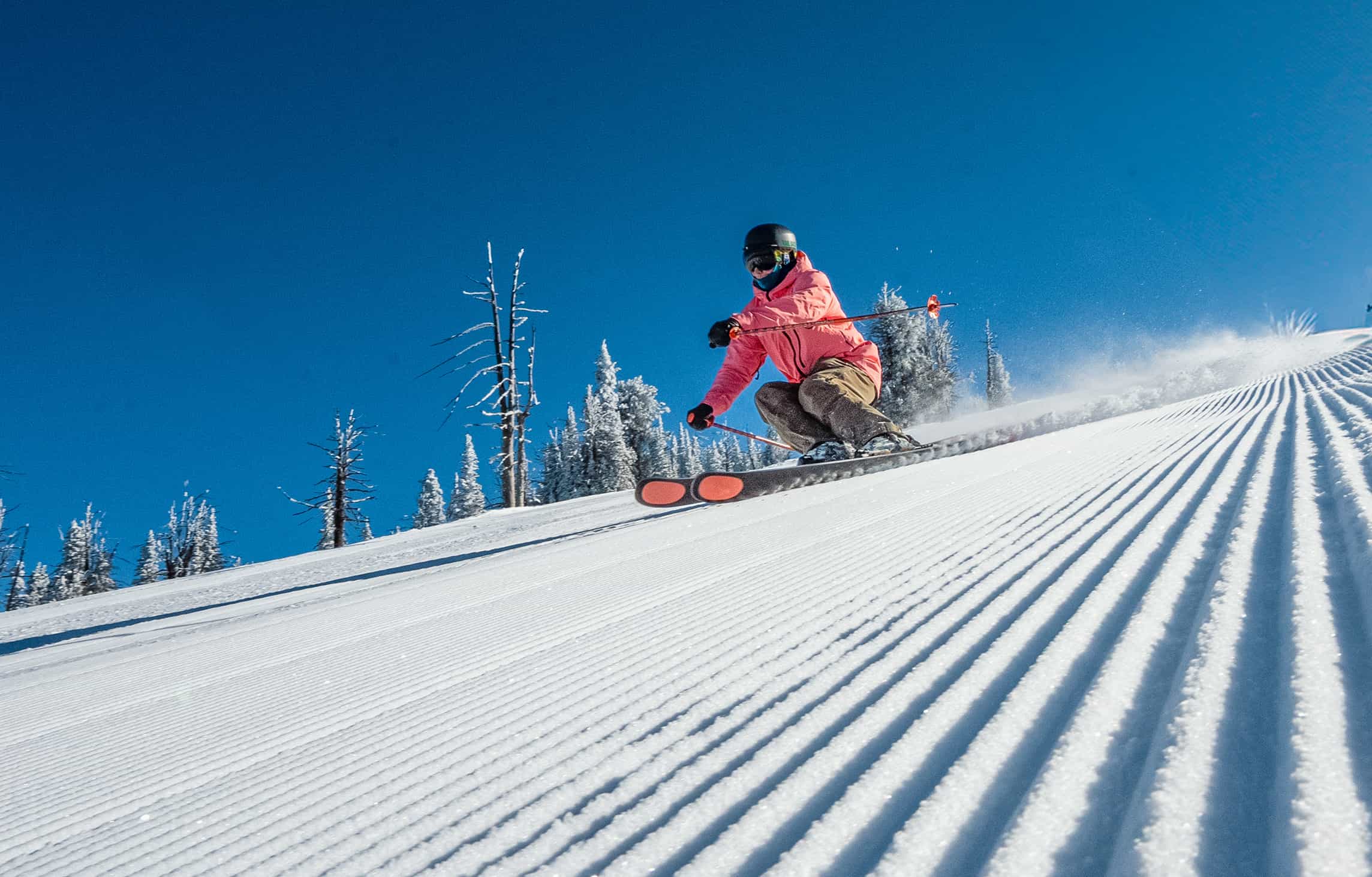Skier on fresh corduroy with blue skies