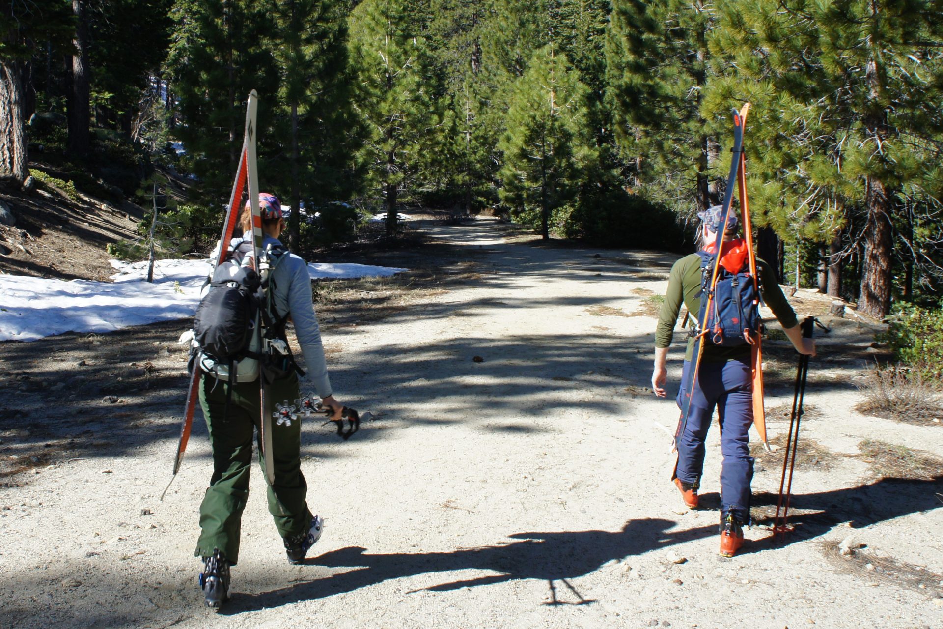 two backcountry skiers walking on a snow free road