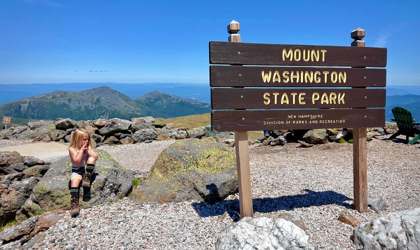 Young hiker sitting at the top of Mount Washinton