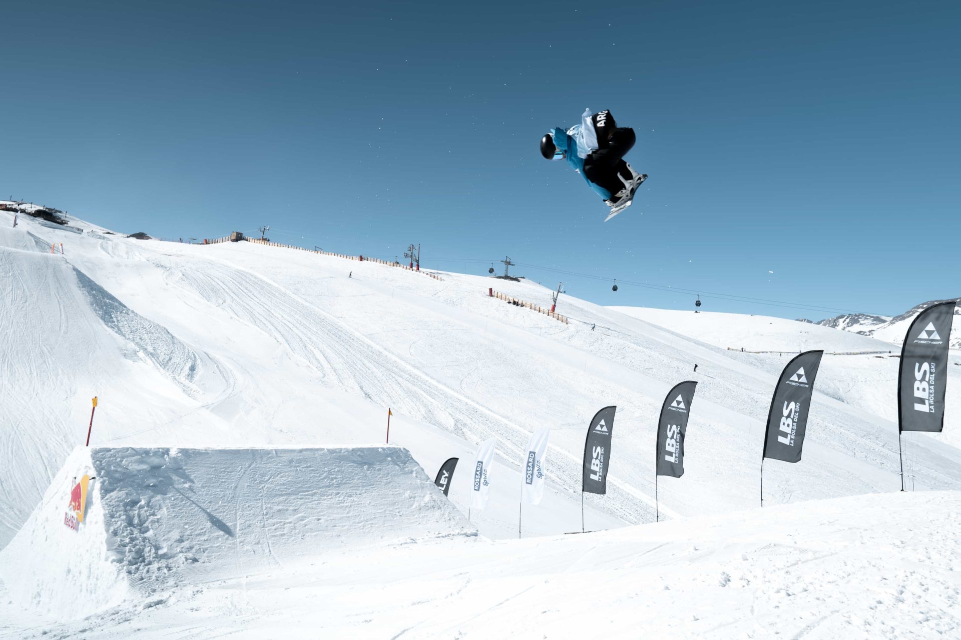 Snowboarder gets big air of a jump with blue skies in the background at Valle Nevado Andes Cup