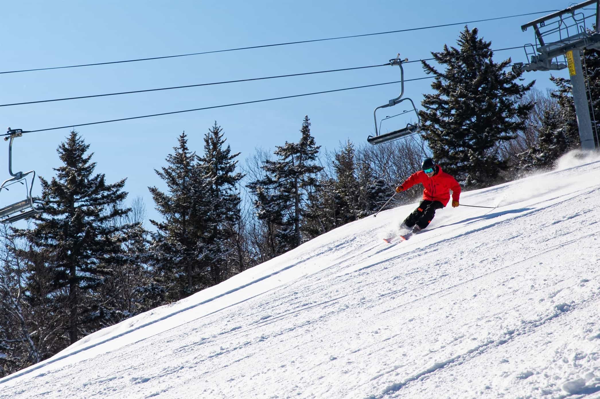 skier in red jacket making turn beneath lift at Ragged Mountain, NH