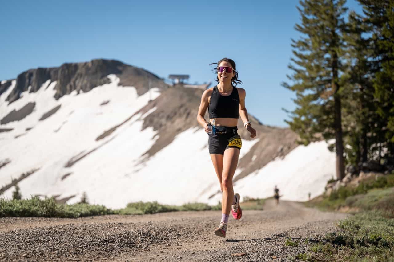 runner on trail at Palisades Tahoe with snow mountain and ski lift in the background